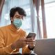 portrait of sick man wearing medical masks using mobile phone during virus epidemic lockdown. social distancing concept on corona virus