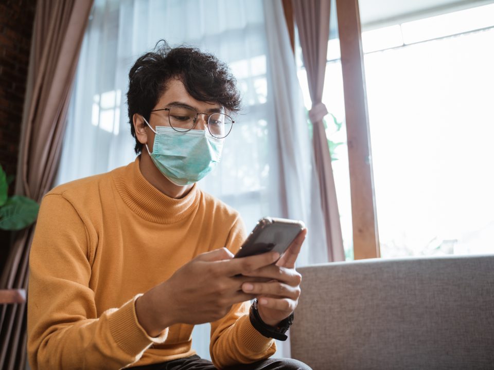 portrait of sick man wearing medical masks using mobile phone during virus epidemic lockdown. social distancing concept on corona virus