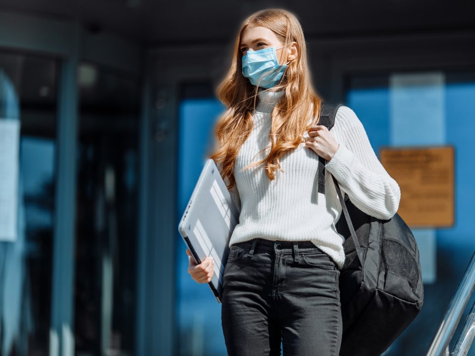 Beautiful young girl in a mask from coronovirus, student on the background of educational envy, women returning from work, remote work, covid-19, against the background of a glass business building